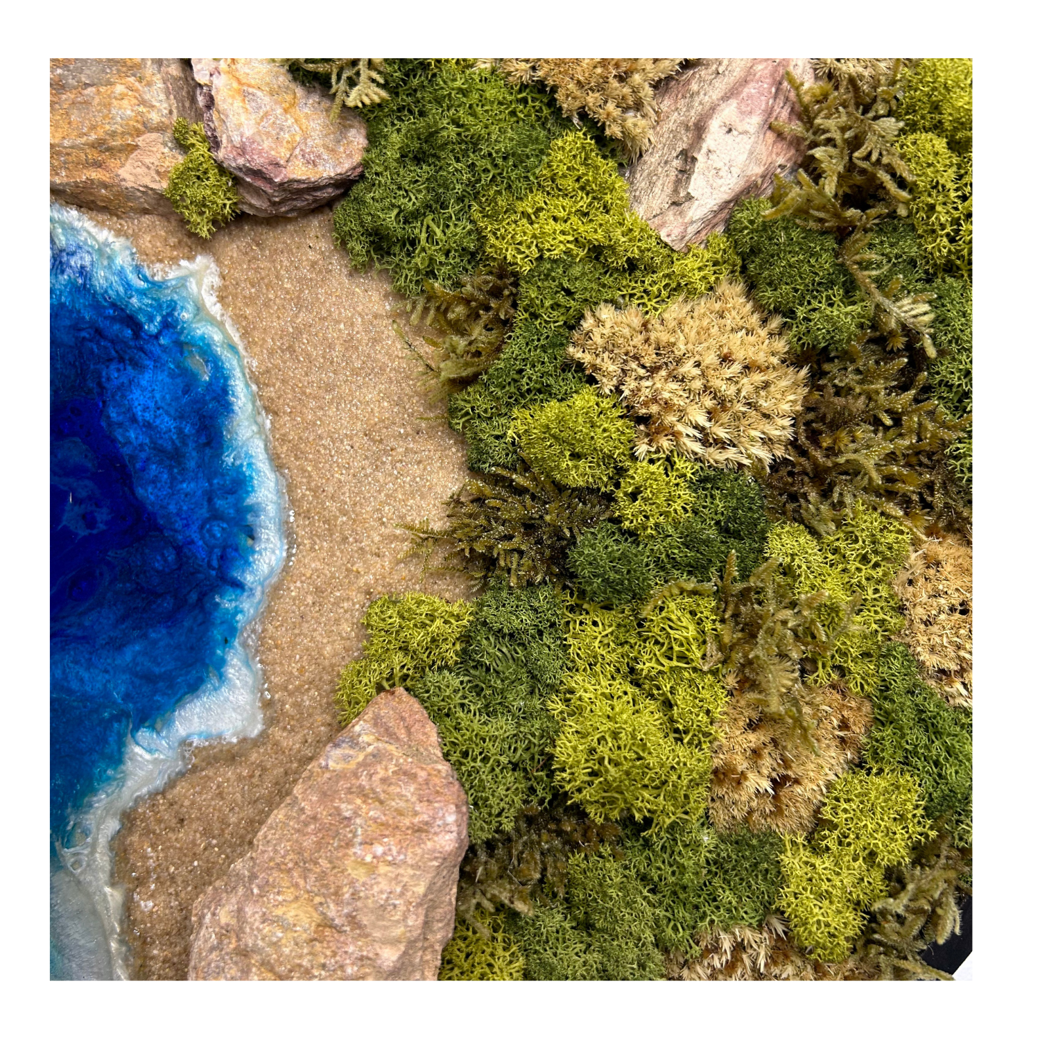 Detailaufnahme Moosbild und Meerbild in einem runden Rahmen aus Holz. Es ist inspiriert von nordischen Küsten: Weite Sträne, ein Ozean aus Epoxidharz, Steine und erdiges, helles Moos wie Bollenmoos, Islandmoos und Flachmoos.