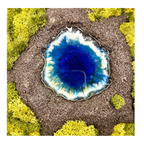 Frontalaufnahme: Moosbild mit einem modellierten Vulkan. In der Mitte des Vulkans ist ein blauer See