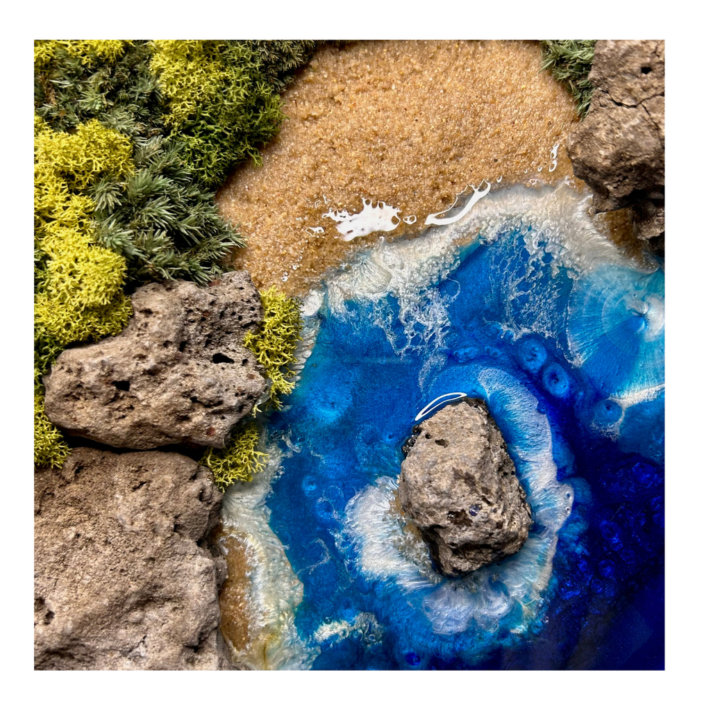 Nahaufnahme vom Strand, Meer und den Wellen des Moos- und Meerbildes "Sardinien" mit einer rauen Küste aus Natursteinen und einem wilden Meer aus Epoxidharz, das sich an den Wellen bricht.  Das Bild enthält Moos, Sand und echten Stein.  