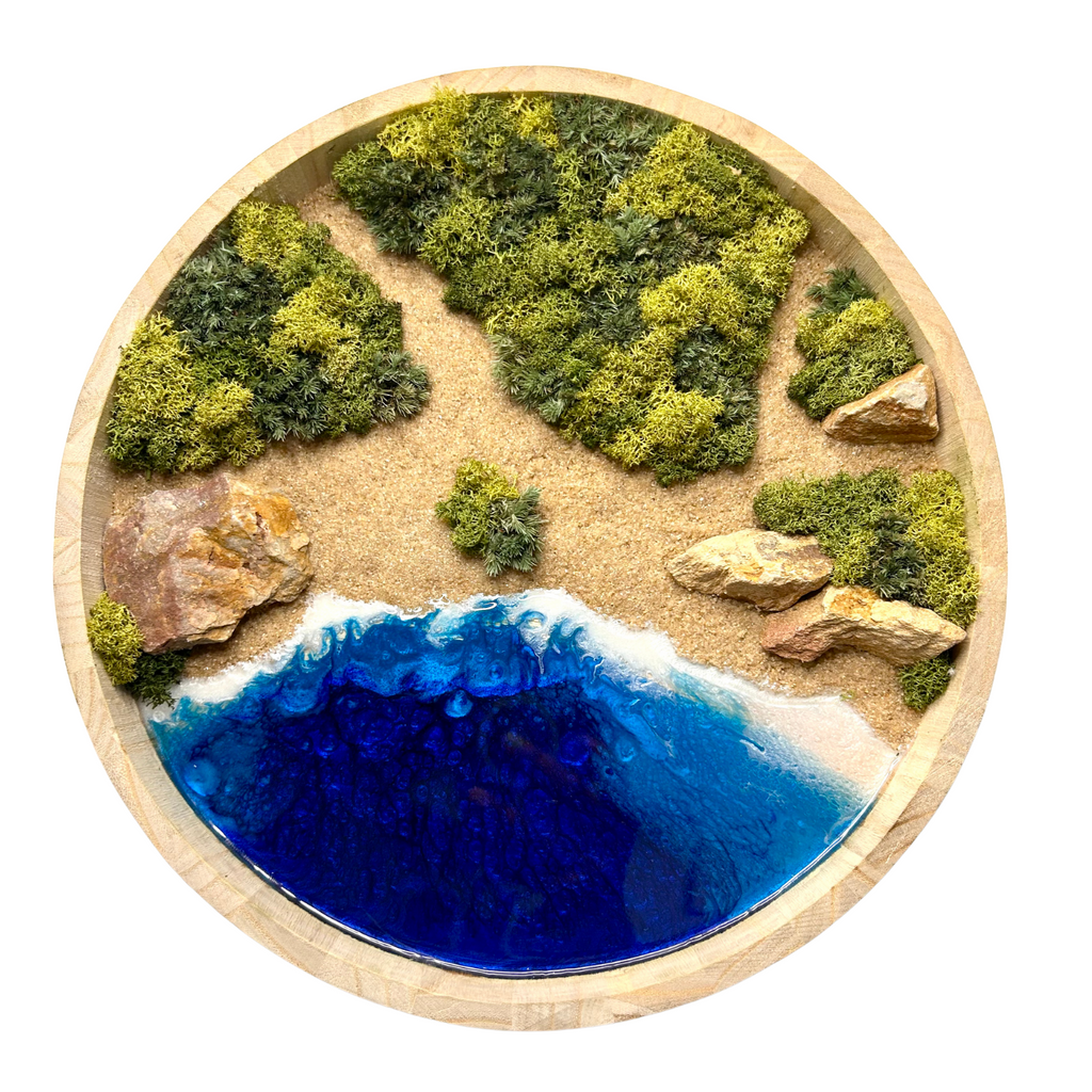Moos- und Meerbild "griechische Bucht" mit einer rauen Küste aus hellen Natursteinen und einem Meer aus Epoxidharz.  Das Bild enthält Moos, Sand und echten Stein.  Es ist in einem runden Rahmen aus leichtem Holz. 