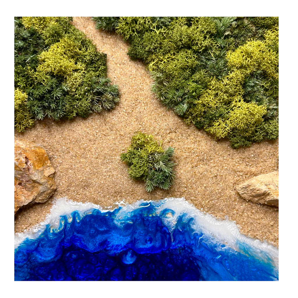 Nahaufnahmen Moos- und Meerbild "griechische Bucht" mit einer Küste aus hellen Natursteinen und einem Meer aus Epoxidharz.  Das Bild enthält Moos, Sand und echten Stein.  Es ist in einem runden Rahmen aus Naturholz. 