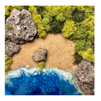 Detailansicht: Moos- und Meerbild "Versteckte Bucht" im schwarzen runden Holzrahmen mit Sandstrand und einem Meer aus blauem Epoxidharz. In das Bild sind Lavasteine eingebaut und mit viel Liebe zum Detail feinste Moosspitzen aus konserviertem Moos eingebaut, die teilweise aussehen wie Palmwedel. 