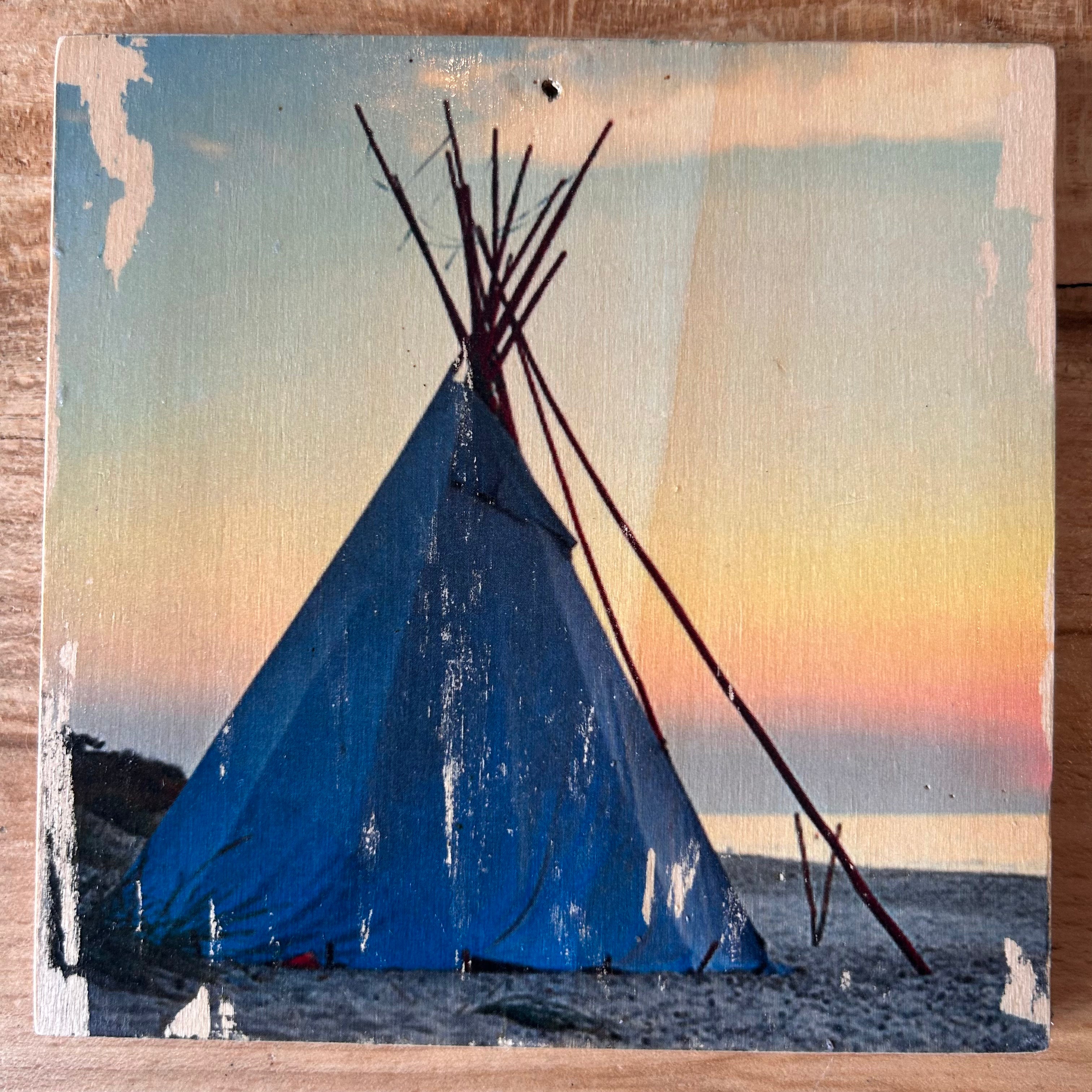 Ein Tipi steht bei Sonnenuntergang am Strand. Ruhig, einsam, mit Blick auf das Weite, ruhige Meer, während die Sonne im Wasser versinkt. Format 15x15cm. Handgefertigter Fotodruck auf Holz 