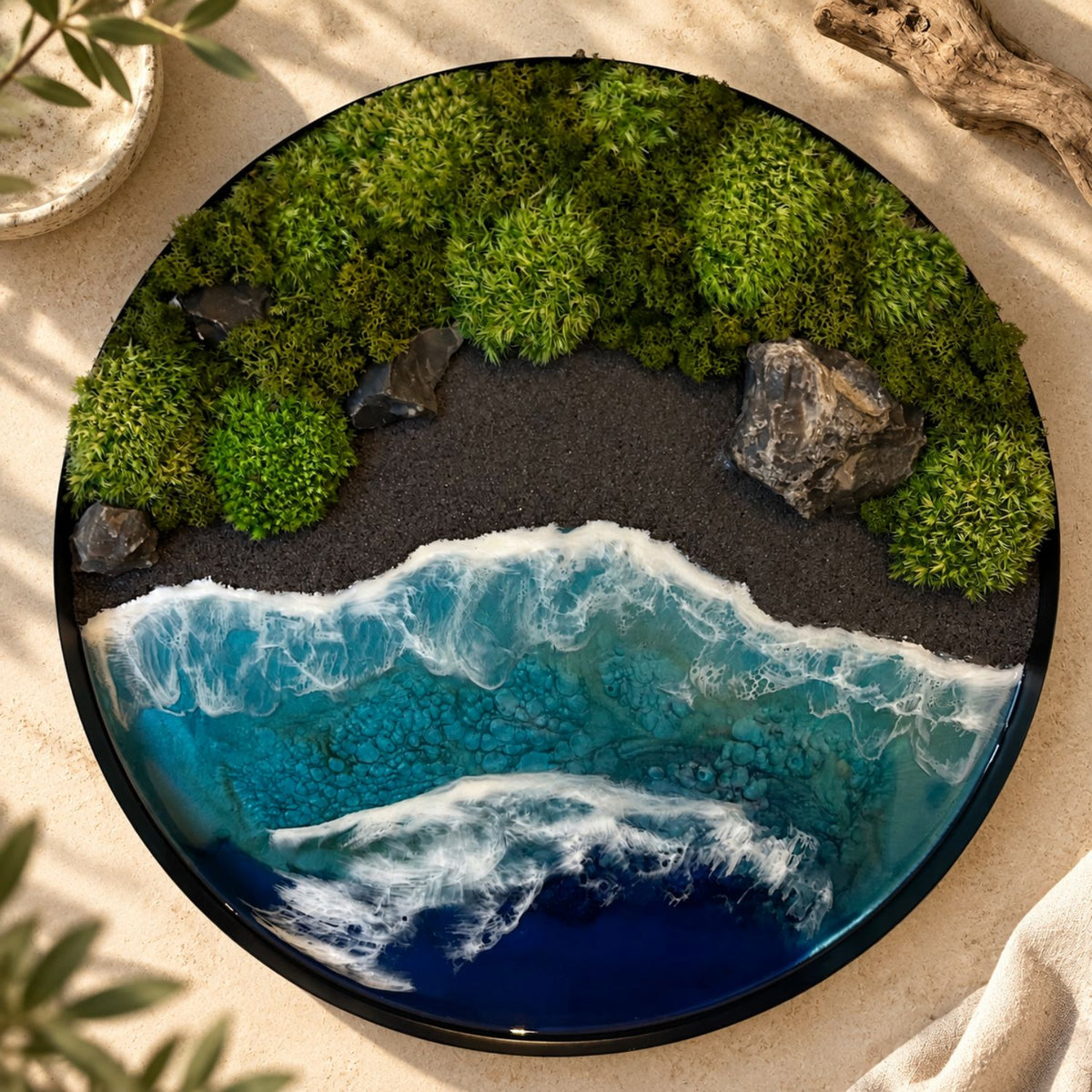 Handgemachtes Moosbild "Wildes Paradies" von Eva Brandenburg, Moos und Meer. Das Bild besteht aus Naturmaterialien: Sand, konserviertem Moos, Natursteinen und einem handgegossenen Meer aus Resin. Es hat einen einem Durchmesser von 40cm. Der Rahmen ist aus Metall. 
