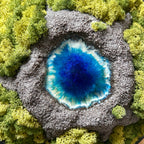 Detailaufnahme des Moosbildes "VulkanSee". Ein Moosbild mit einem von Hand modellierten Vulkan in der Mitte, der sich dimensional aus dem Bilderrahmen heraus bewegt. In der Mitte des Vulkans befindet sich ein Vulkansee aus Resin. 