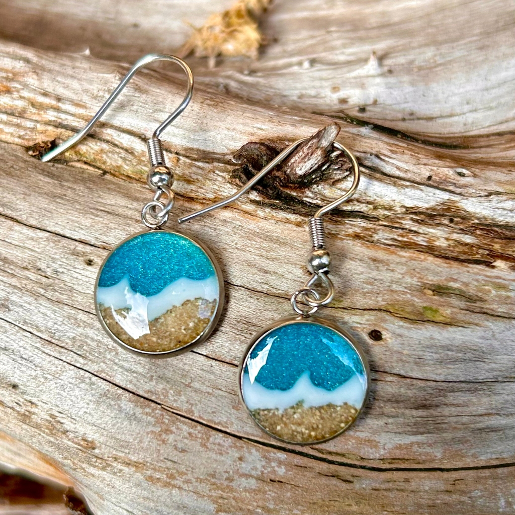 Hängeohrringe in Silber. Mit Epoxidharz wurde ein Meer (türkis mit weißen Wellen) hinein gegossen. Der Strand besteht aus echtem Sand aus Tarifa. 