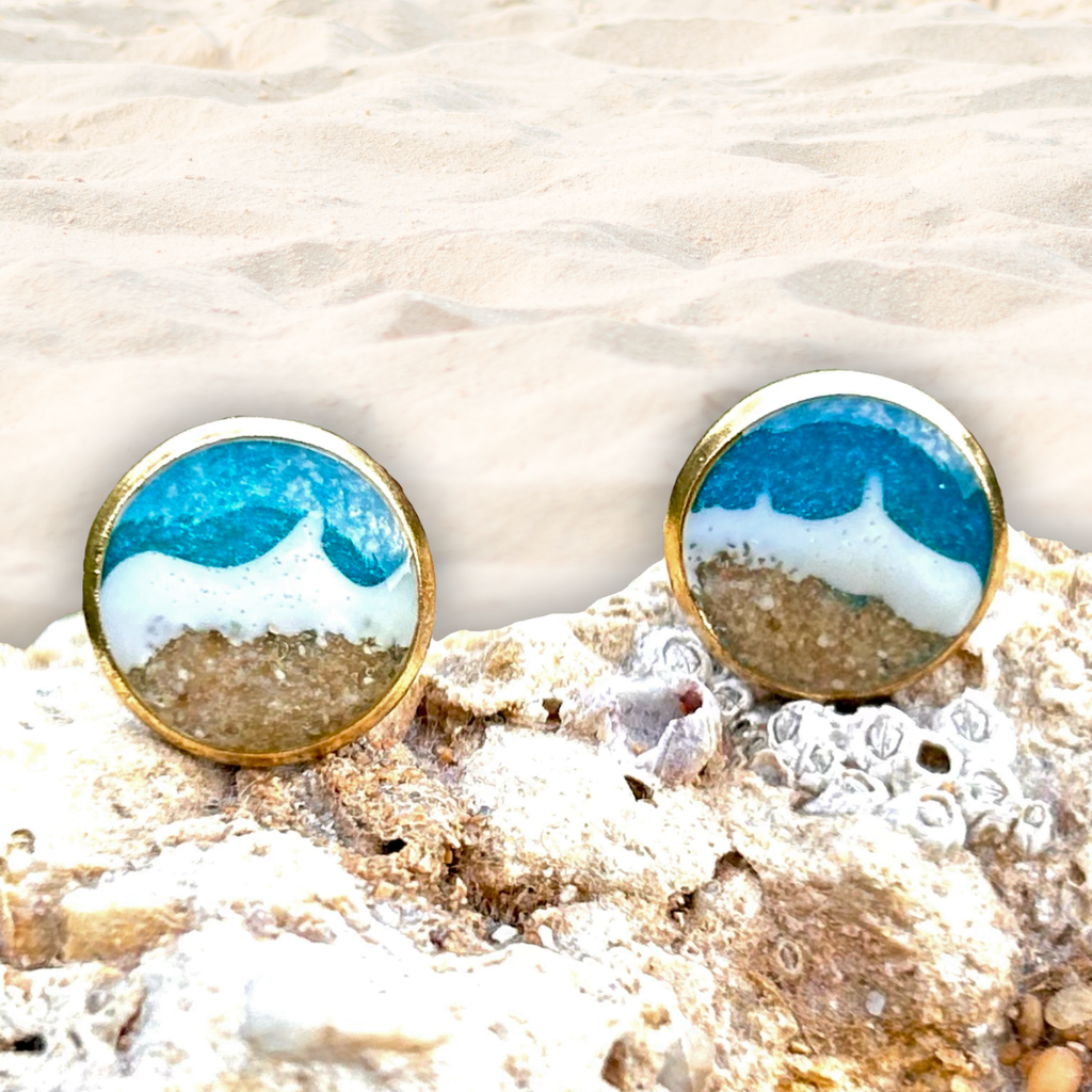 Maritime Ohrstecker in Gold. Mit Resin wurde ein Meer (türkis mit weißen Wellen) hinein gegossen. Der Strand besteht aus echtem Sand aus Tarifa. 