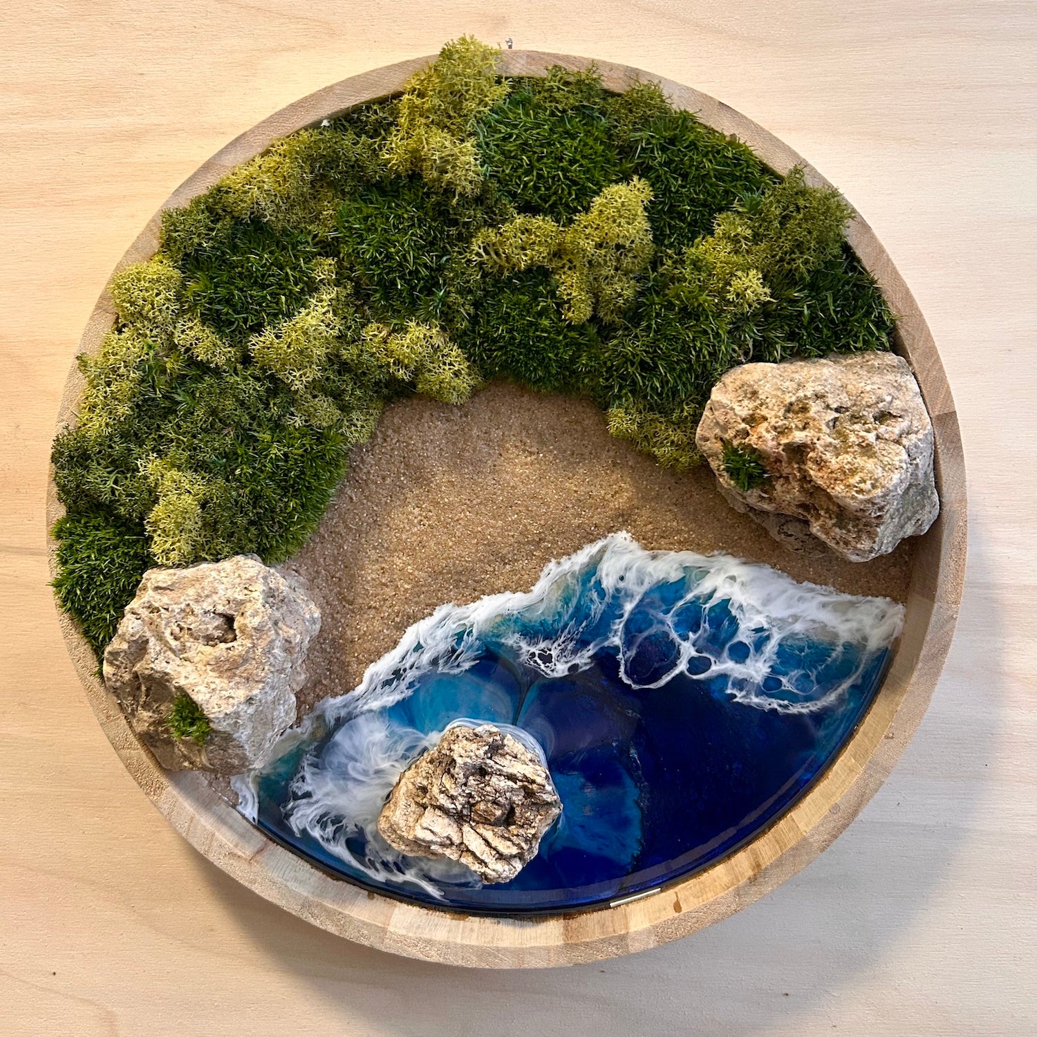  Moosbild "Goldener Strand" in einem runden Rahmen aus Bambus . Hier sieht man ein Meer mit Wellen aus Resin, einen Strand mit hellem Sand, Natursteine und grünes, konserviertes Moos. Naturkunst von Moos und Meer in Oberhausen.