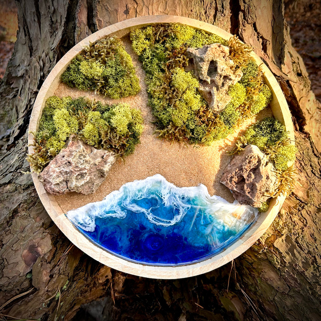 Rundes Moos- und Meerbild mit grünen Mooslandschaften, sandfarbenen Wegen, Natursteinen und tiefblauem Resin-Meer mit schäumenden Wellen, eingebettet in einen Holzrahmen.