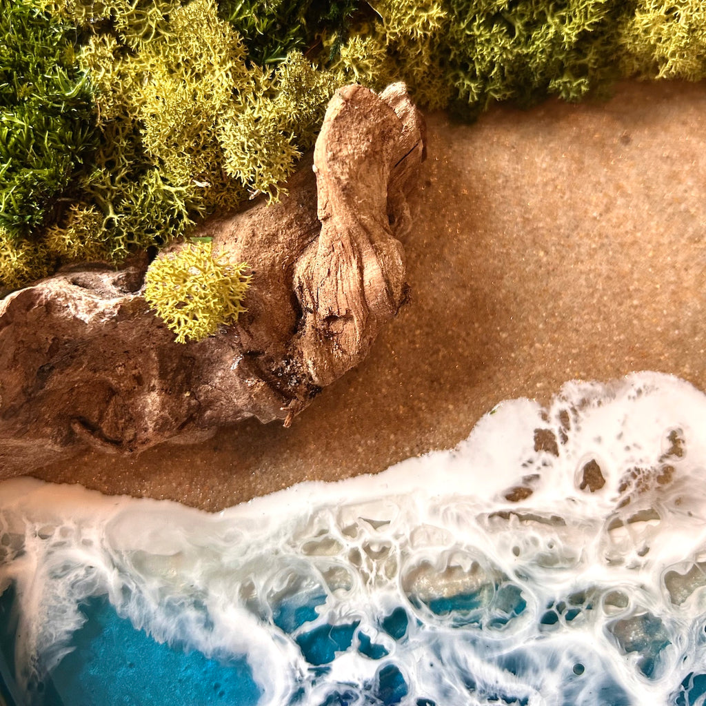 Detailaufnahme 2 des Moosbild "Treibholzstrand" . Hier sieht man ein Meer mit Wellen aus Resin, einen Strand mit hellem Sand, Treibholz und grünes, konserviertes Moos. Naturkunst von Moos und Meer in Oberhausen.