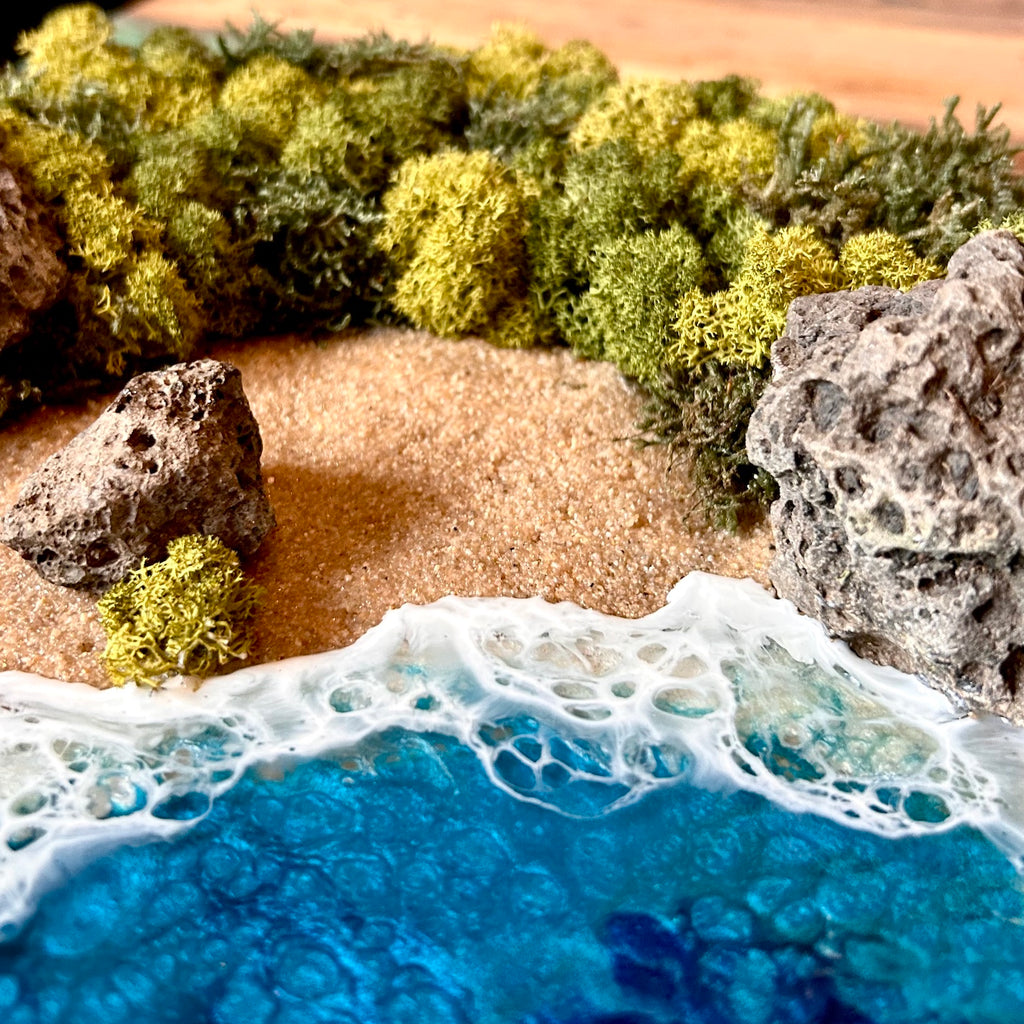 Detailaufnahme 2 des Moosbild "Versteckte Bucht" . Hier sieht man ein Meer mit Wellen aus Resin, einen Strand mit hellem Sand, Natursteine und grünes, konserviertes Moos. Naturkunst von Moos und Meer in Oberhausen.